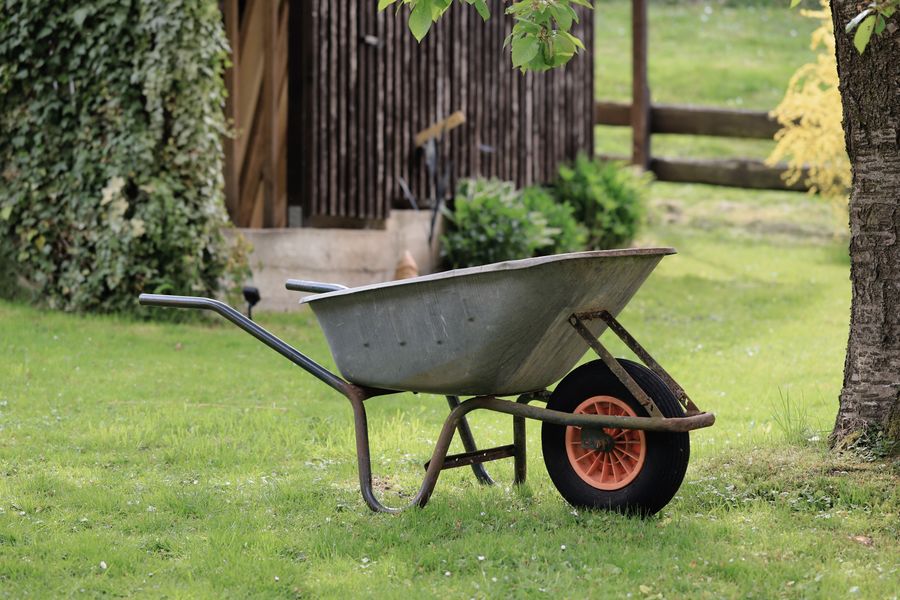 Aufgeräumter Garten mit Schubkarre vor einem Holzschuppen
